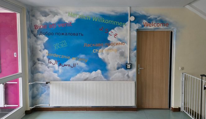 Wandgestaltung mit Wolken und bunten Schriftzügen in einem Flur.